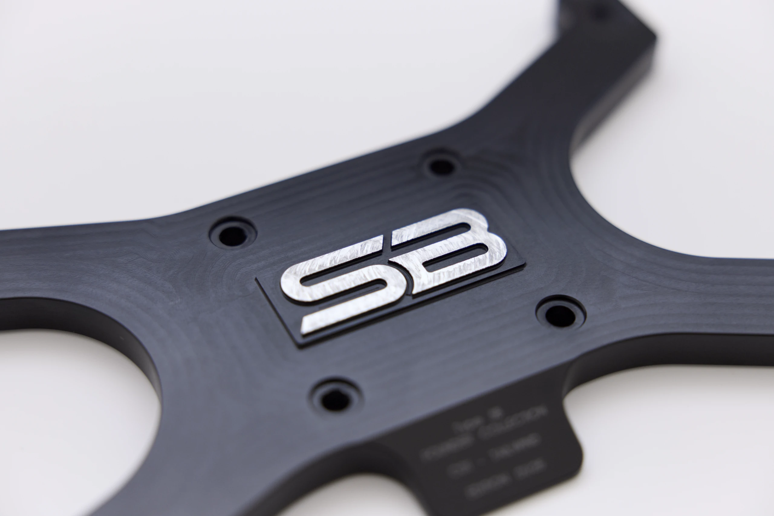 Macro detail of the machined SB mark on the black anodised wheelbase